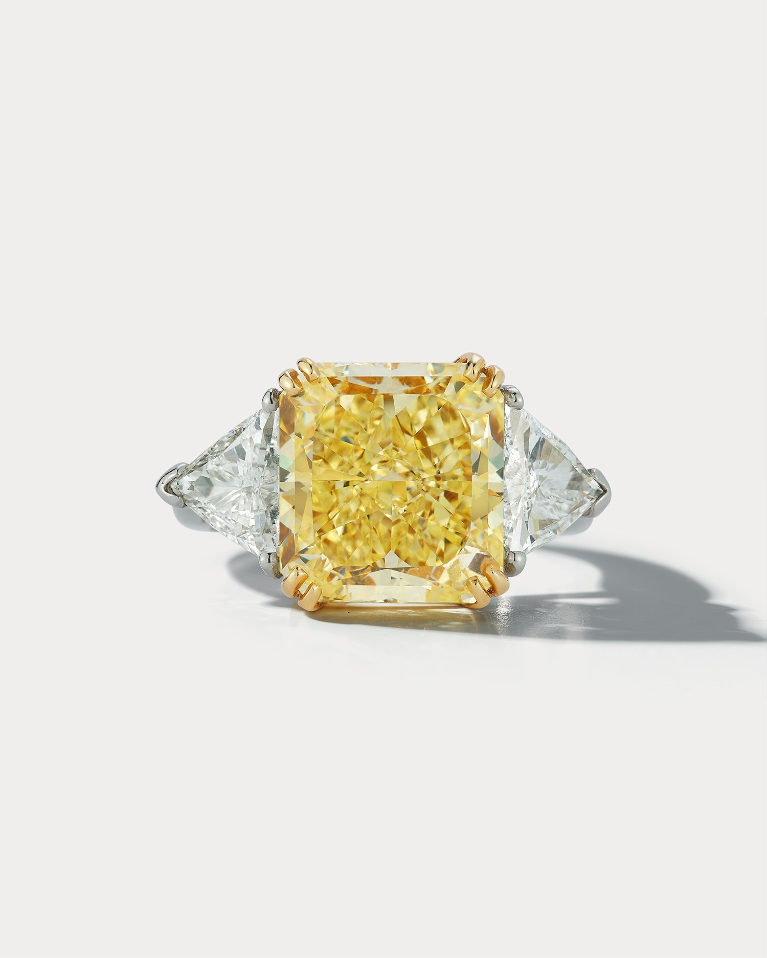 Ammrada 7.49 carat fancy yellow radiant-cut center stone three-stone ring showing the sparkling yellow gemstones and elegant band.