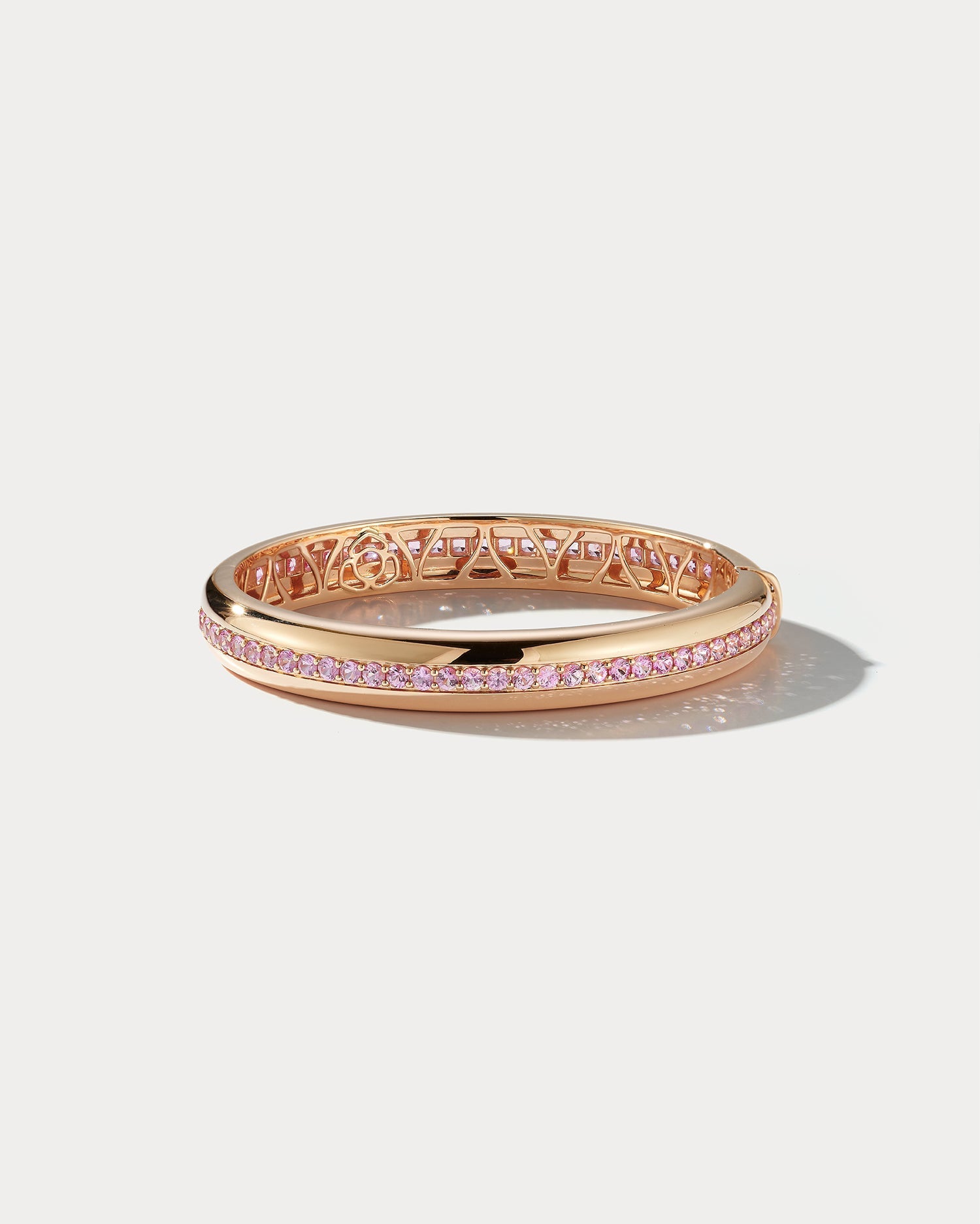 Wide rose gold and pink sapphire bangle by Ammrada, featuring a sleek design with sparkling pink sapphires and a polished finish.