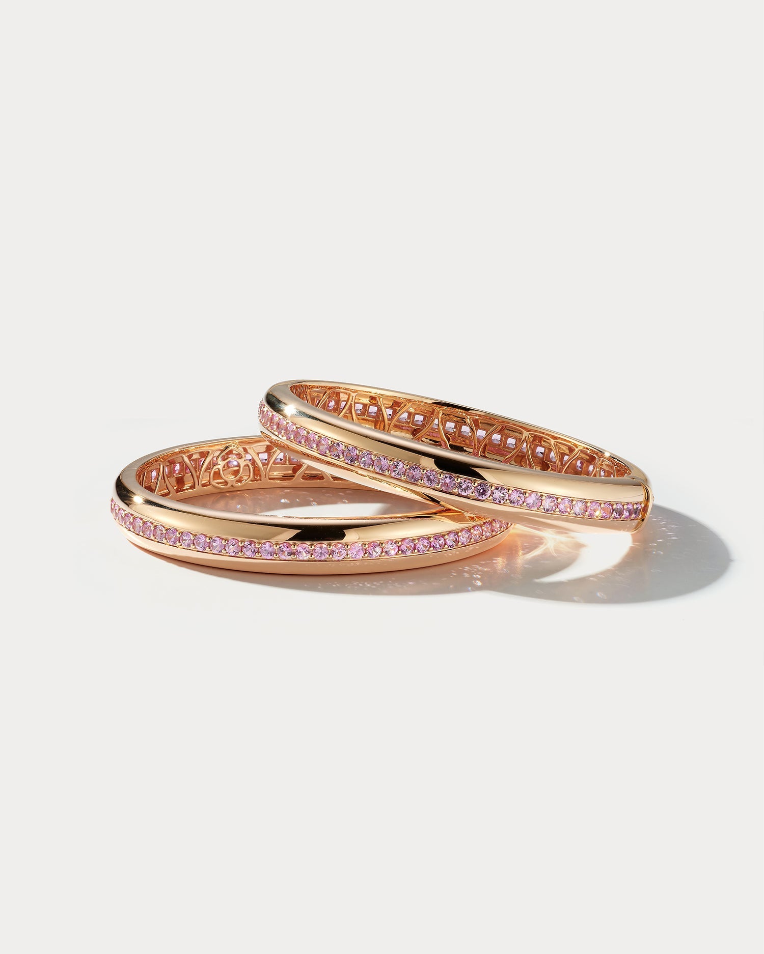 Wide rose gold bangle with pink sapphires from Ammrada, showcasing elegant design and sparkling gemstone accents.
