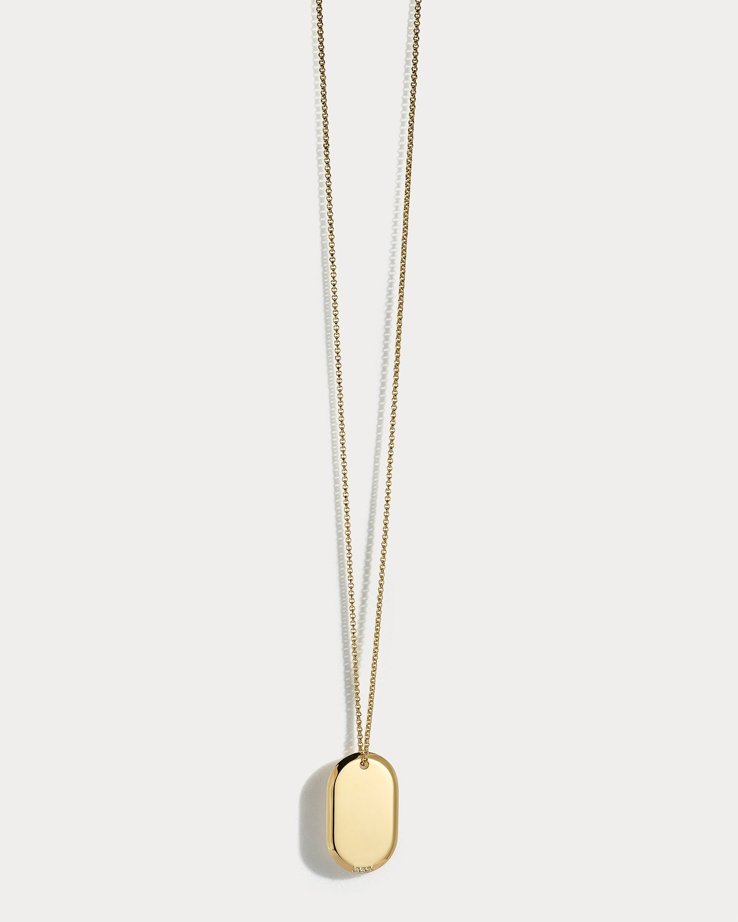 18k yellow gold dog tag necklace with diamonds, featuring Ammrada branding, displayed on a neutral background.