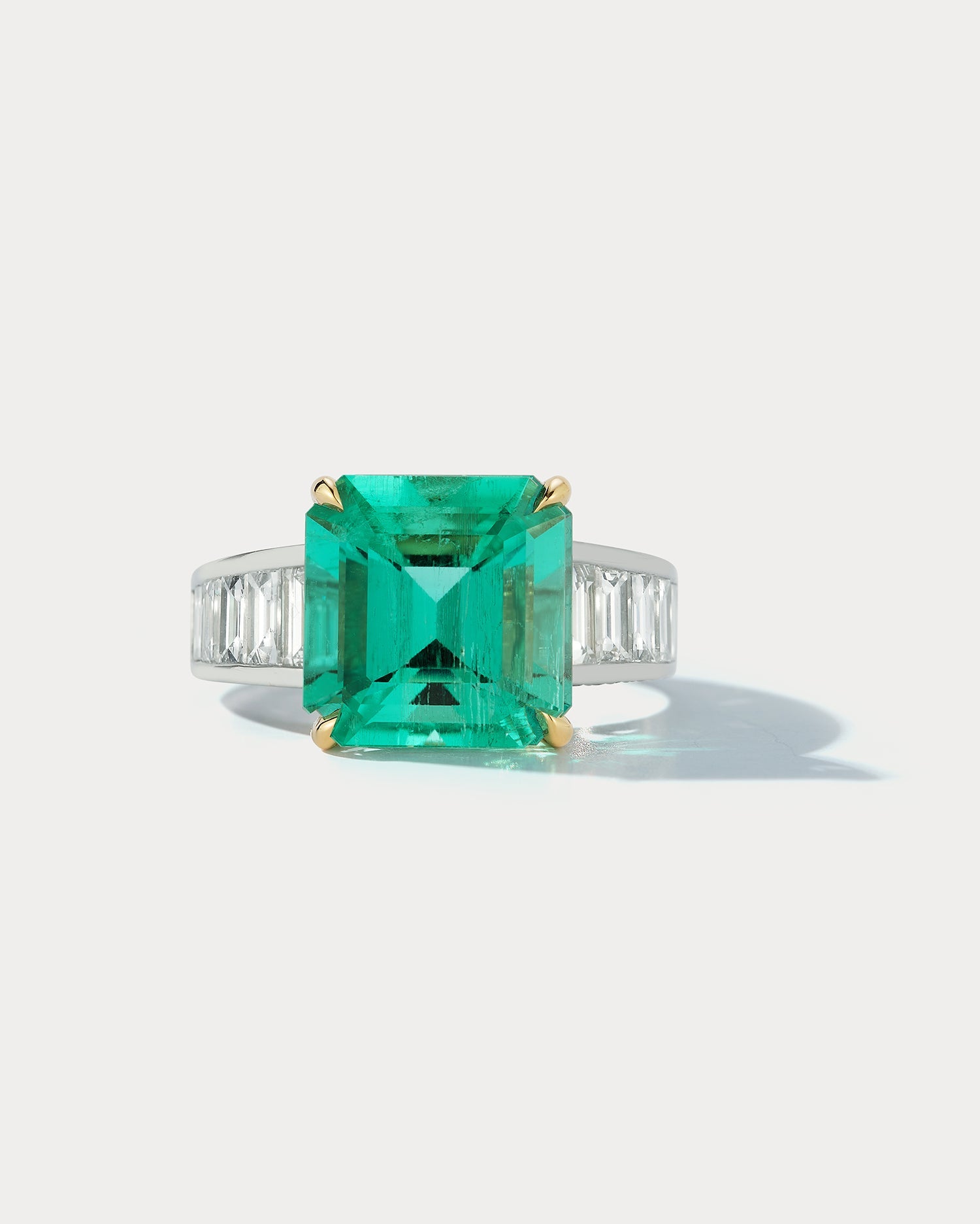 Ammrada platinum and 18k yellow gold channel ring set with Colombian Muzo 5.86 emerald cut emeralds, elegant jewelry design.