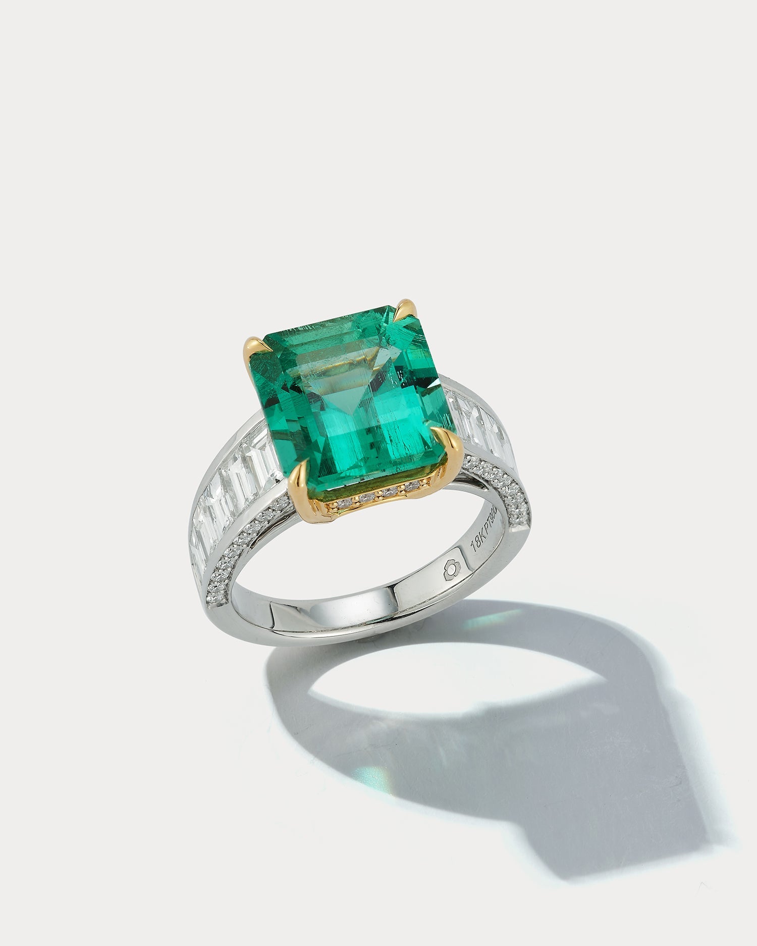 Ammrada platinum and 18k yellow gold channel ring set featuring a Colombian Muzo 5.86 emerald cut emerald gemstone.