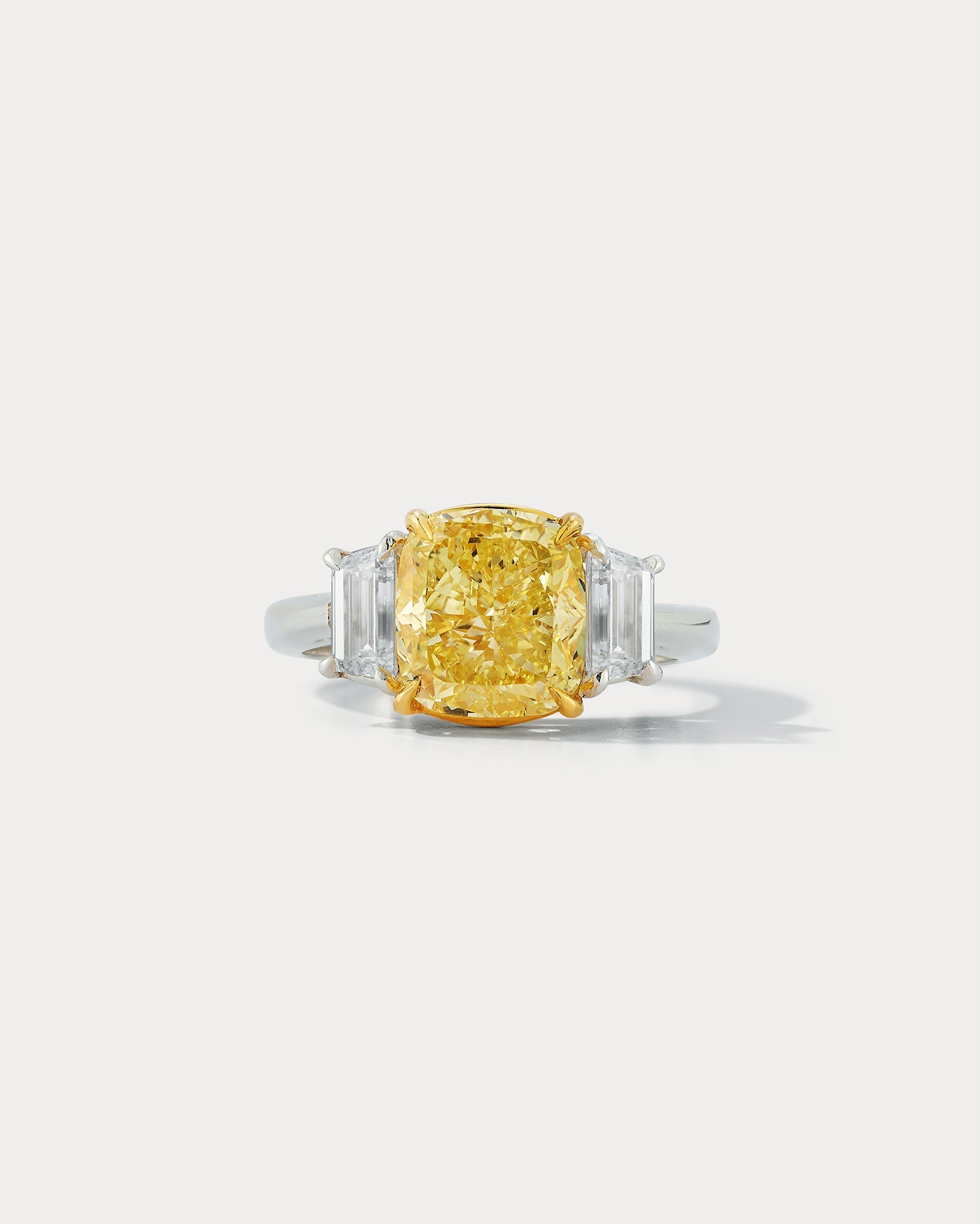 Ammrada 4.01 carat fancy intense yellow cushion-cut center stone three-stone ring with side stones and detailed band.
