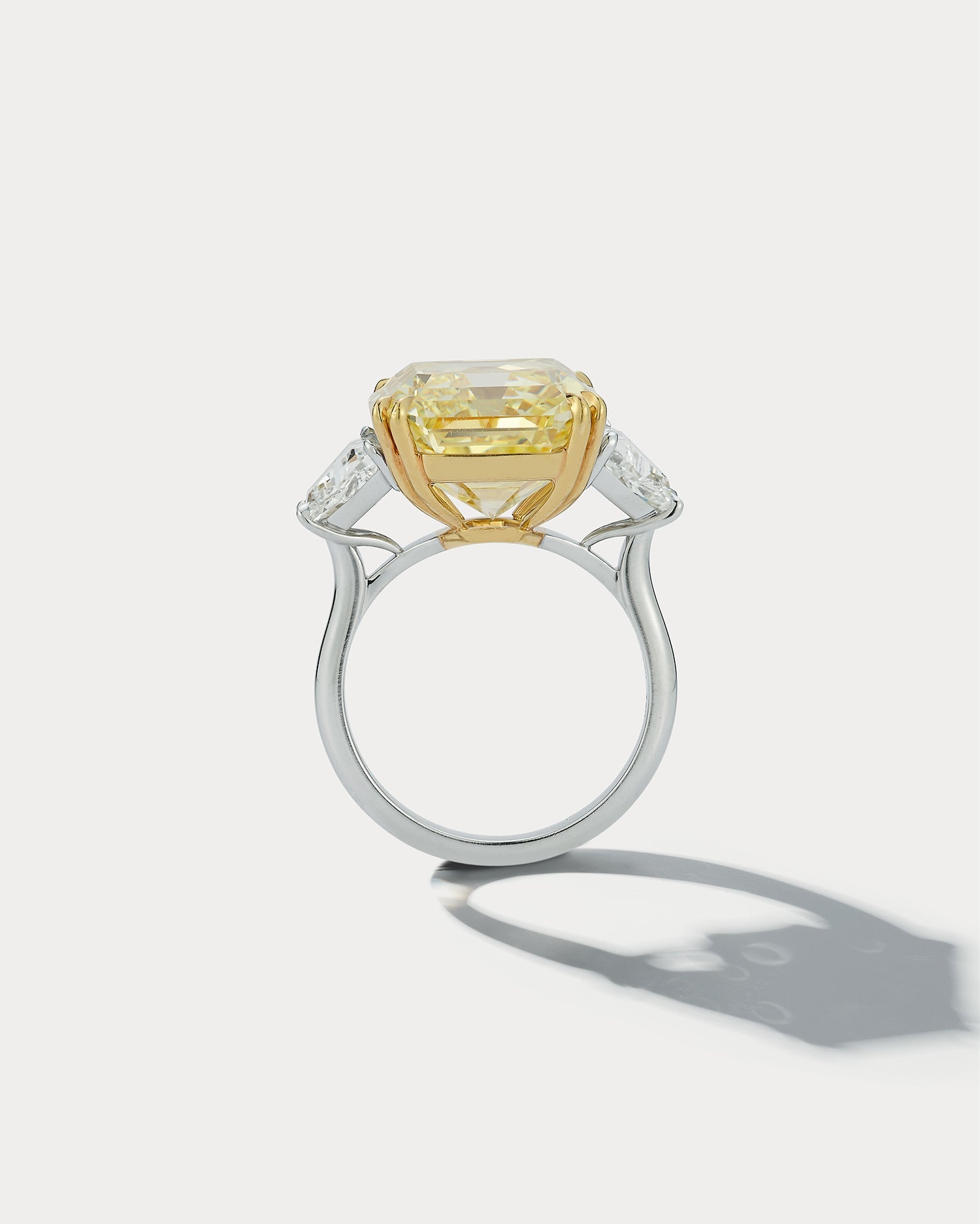 Ammrada 14.36 FIY emerald-cut three-stone ring featuring a central emerald-cut gemstone with side stones, elegant and sparkling.